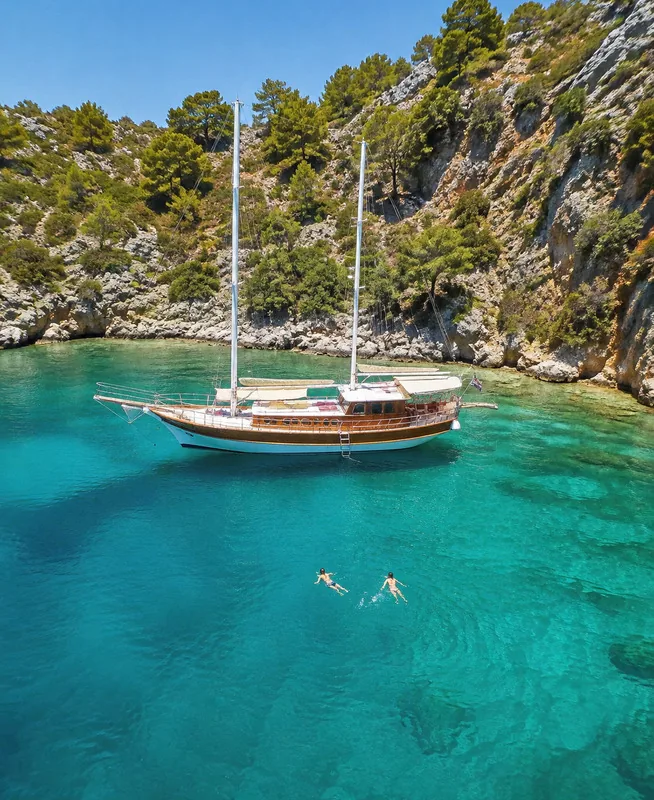Boat anchored in a cove with swimmers in the water
